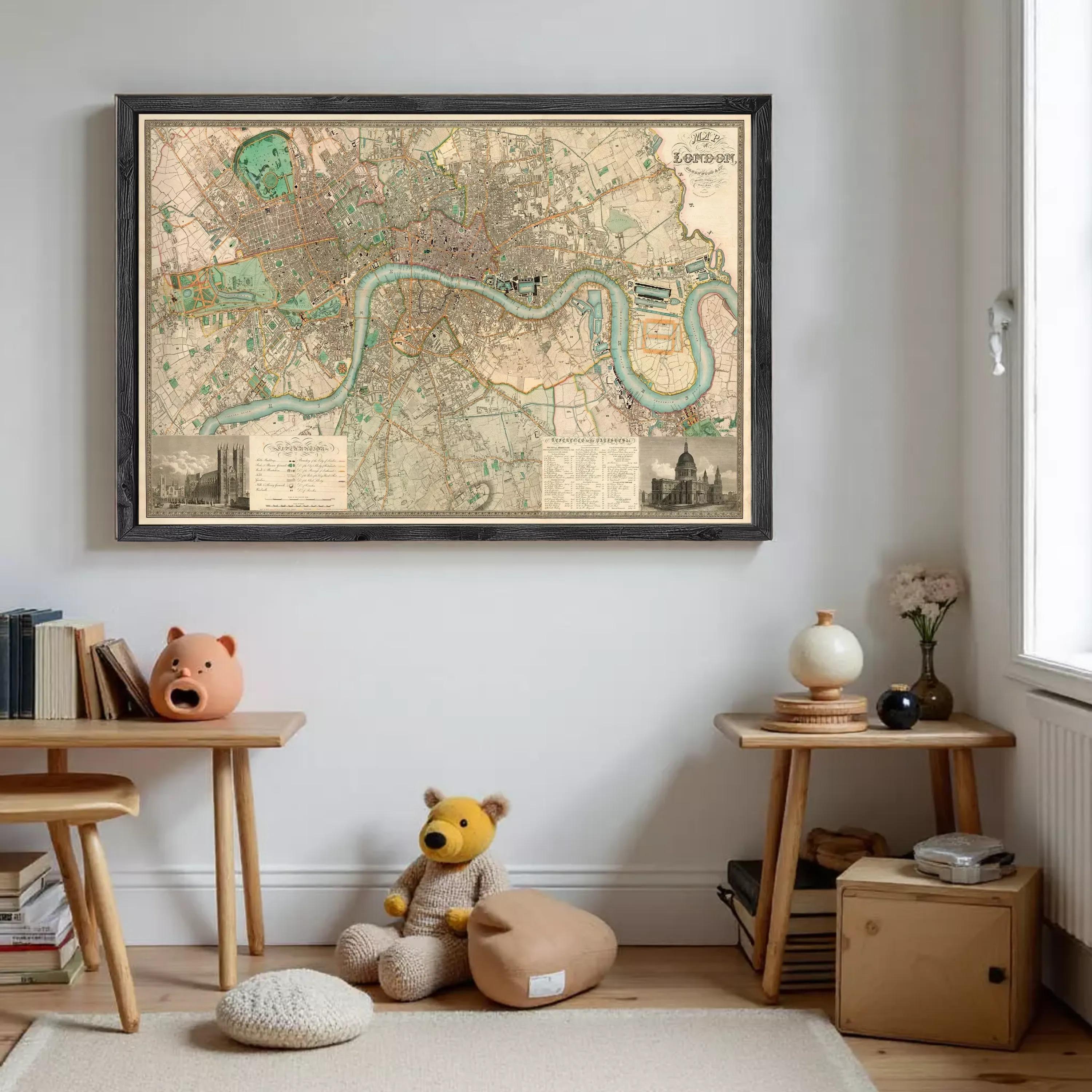 a framed map of London hanging on a wall, with a teddy bear sitting on the floor in front of it.