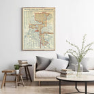 a living room with a framed vintage map of Orlando, Florida, hanging on the wall. The map is surrounded by a variety of decorative elements, including a vase with greenery, books, and a wooden side table.