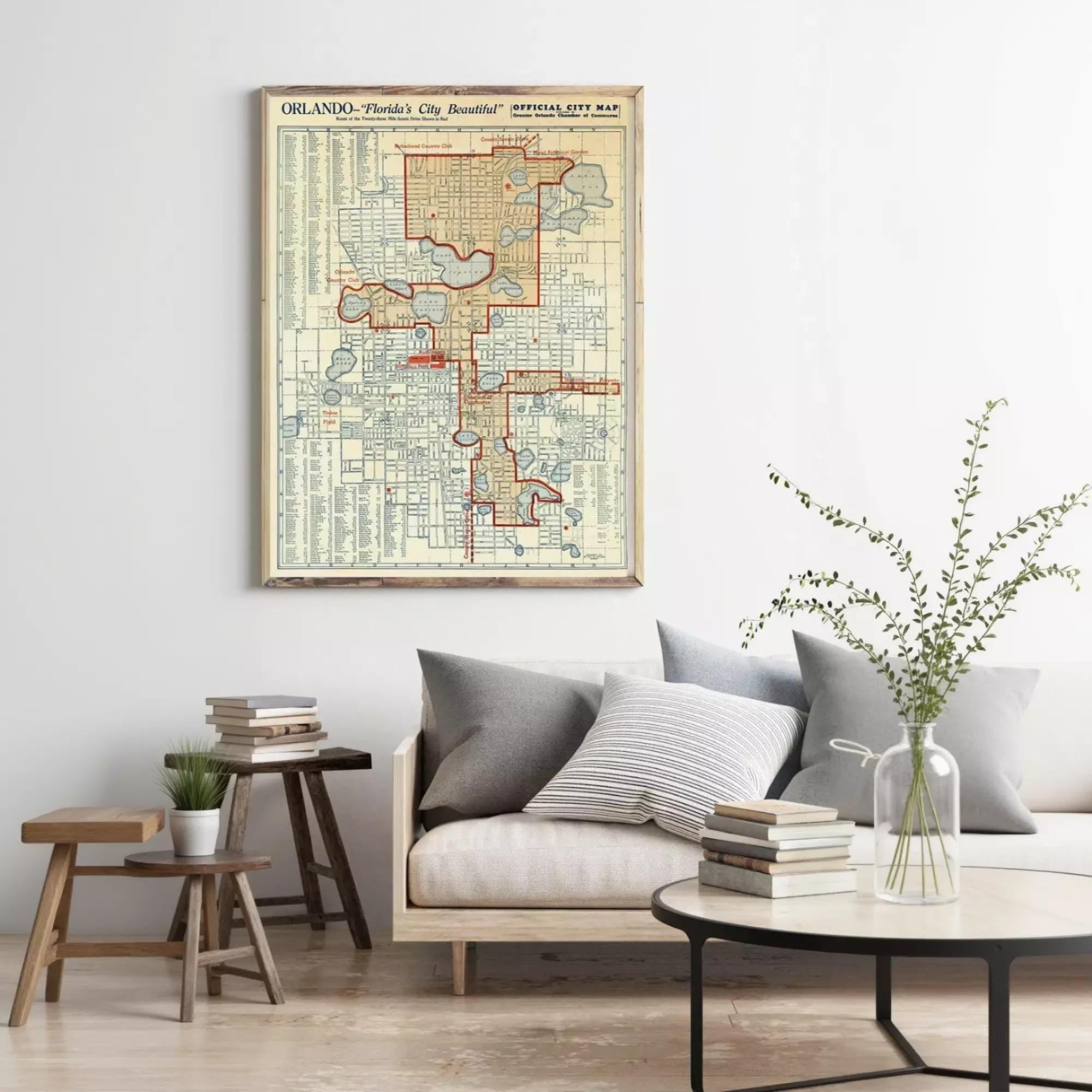 a living room with a framed vintage map of Orlando, Florida, hanging on the wall. The map is surrounded by a variety of decorative elements, including a vase with greenery, books, and a wooden side table.