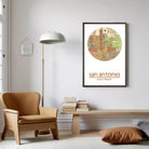 a living room with a brown armchair, a wooden bench, and a lamp. Above the bench, there is a framed map of San Antonio, Texas, with the text "San Antonio" and "29.13.25 39.30 W" printed on it.