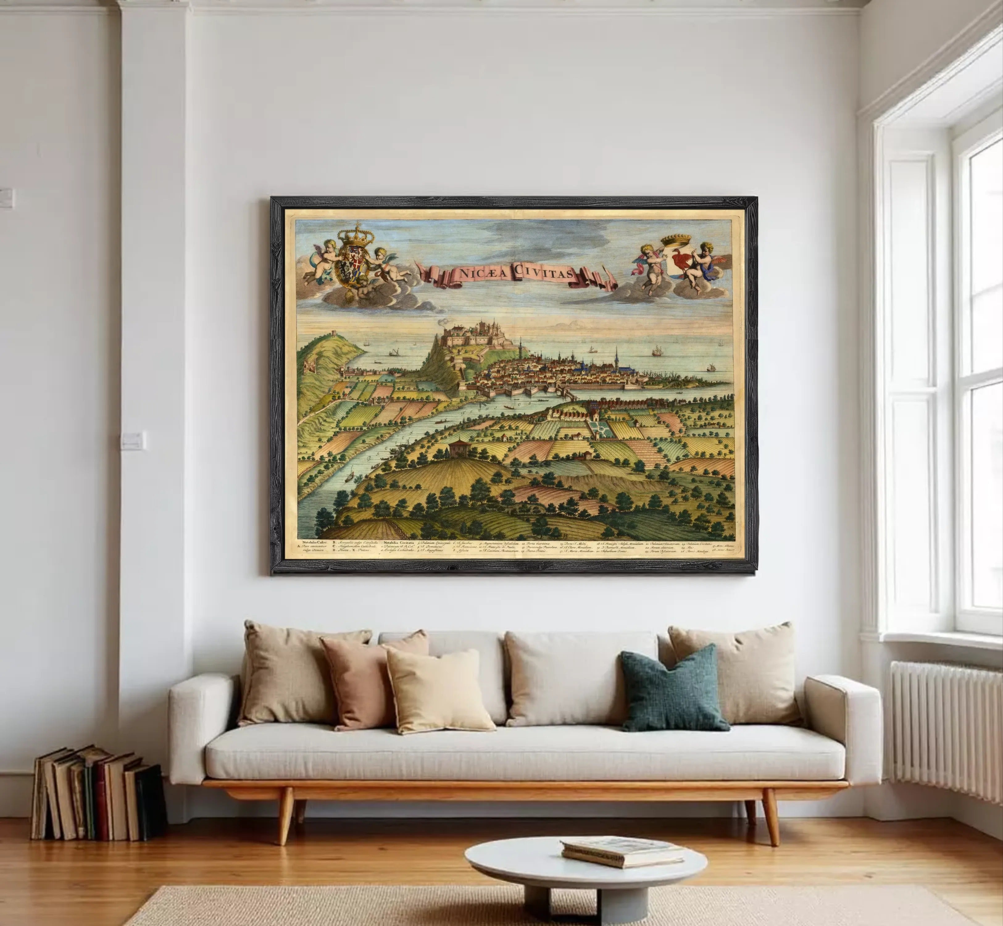 The image is a framed vintage map of a city, depicting a landscape with a river, buildings, and people.