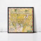 The image is a framed vintage map of a city, likely from the early 20th century, depicting a detailed layout of streets, landmarks, and other geographic features.