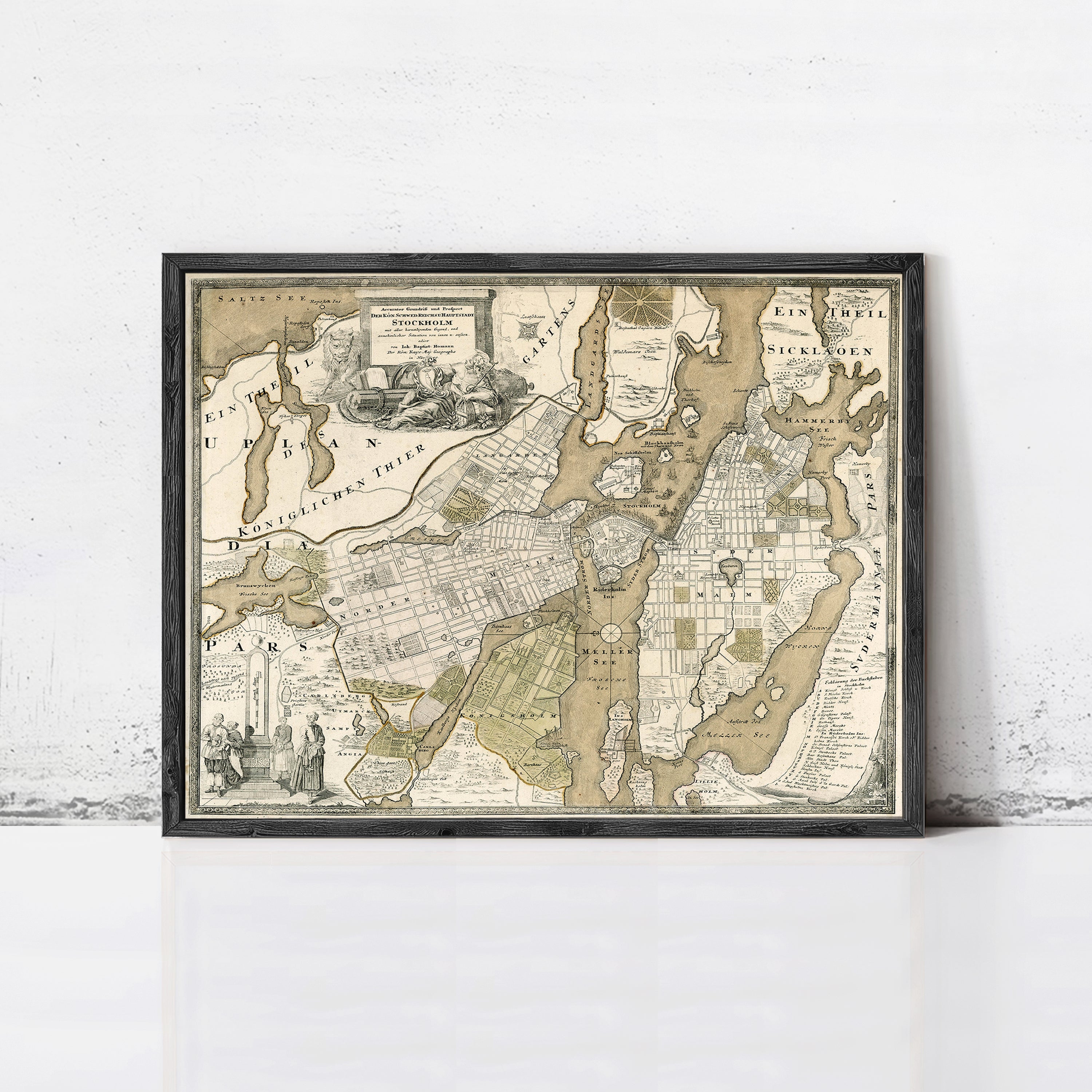 The image is a framed antique map of a city, likely from the 18th century, with detailed cartography and illustrations.